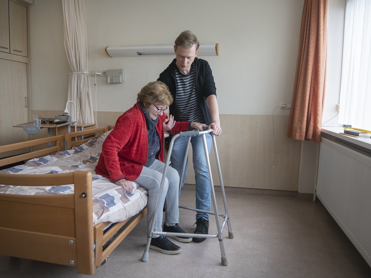 Fysio met oudere in verpleeghuis looprek