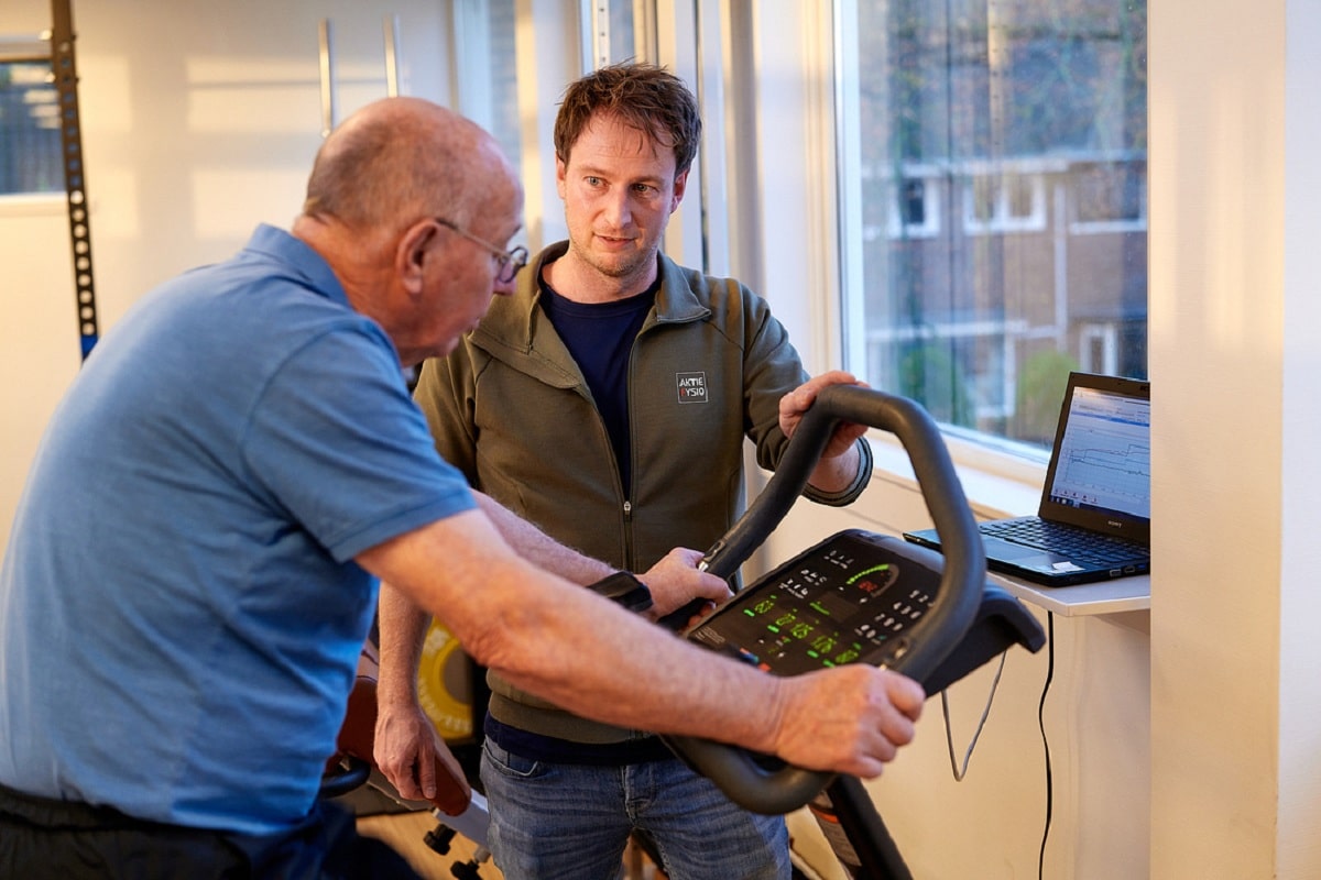 Fysiotherapeut en oudere patient op hometrainer