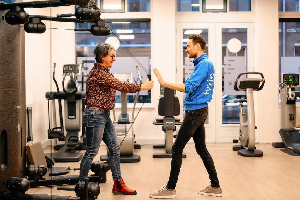 Patient vrouw met fysio man in oefenzaal oefening armen