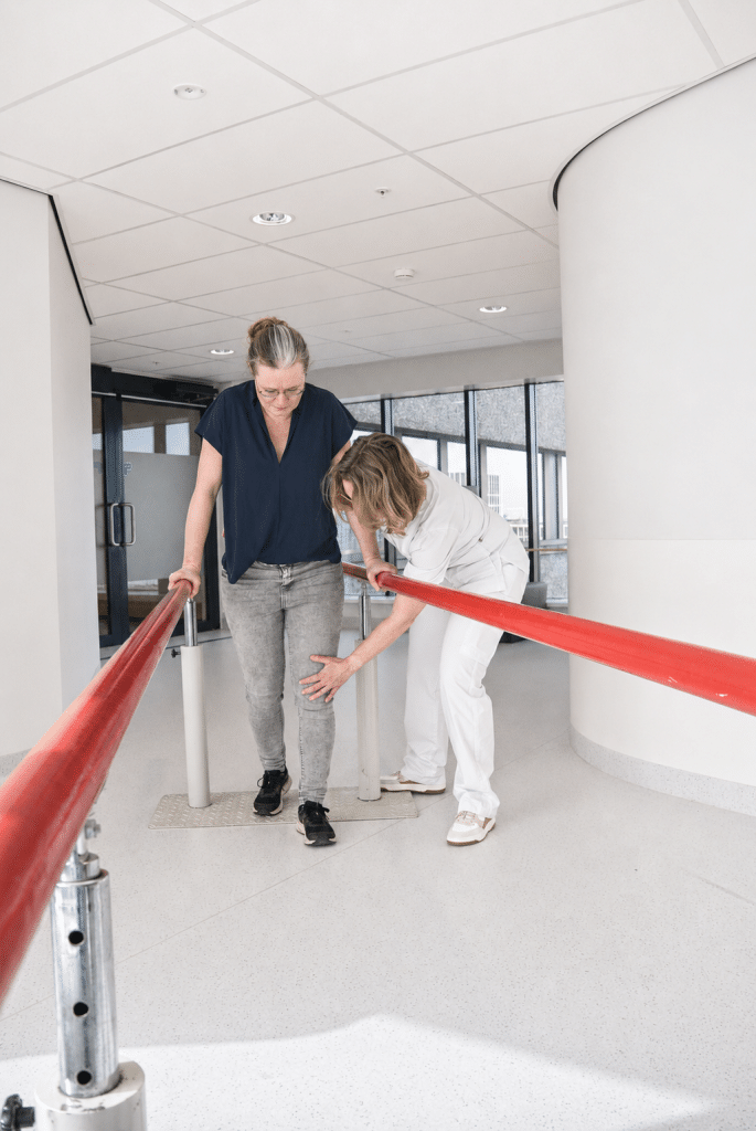 Fysiotherapeut helpt vrouw met lopen langs een brug